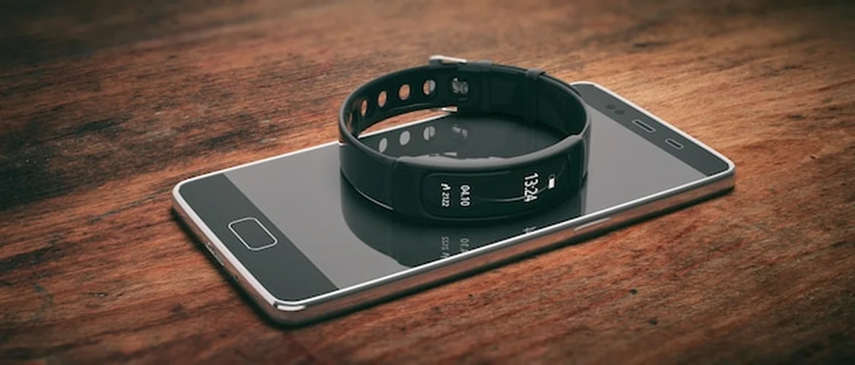 Fitness tracker, inteligentny zegarek i telefon komórkowy na drewnianym tle